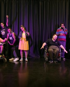 Groups of four and three people on a theatre stage in front of a dark curtain Groups of four and three people on a theatre stage in front of a dark curtain