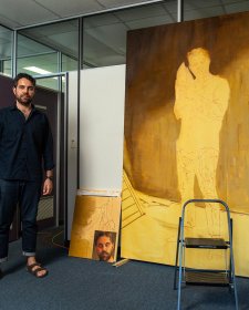 Christopher Bassi standing in an empty office next to a large yellow painting Christopher Bassi standing in an empty office next to a large yellow painting